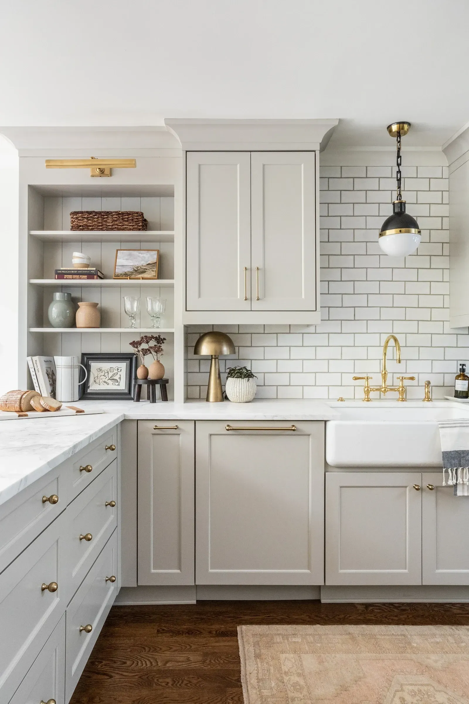 Timeless kitchen with natural wood flooring, light-colored cabinetry, a large island, and warm brass accents.
